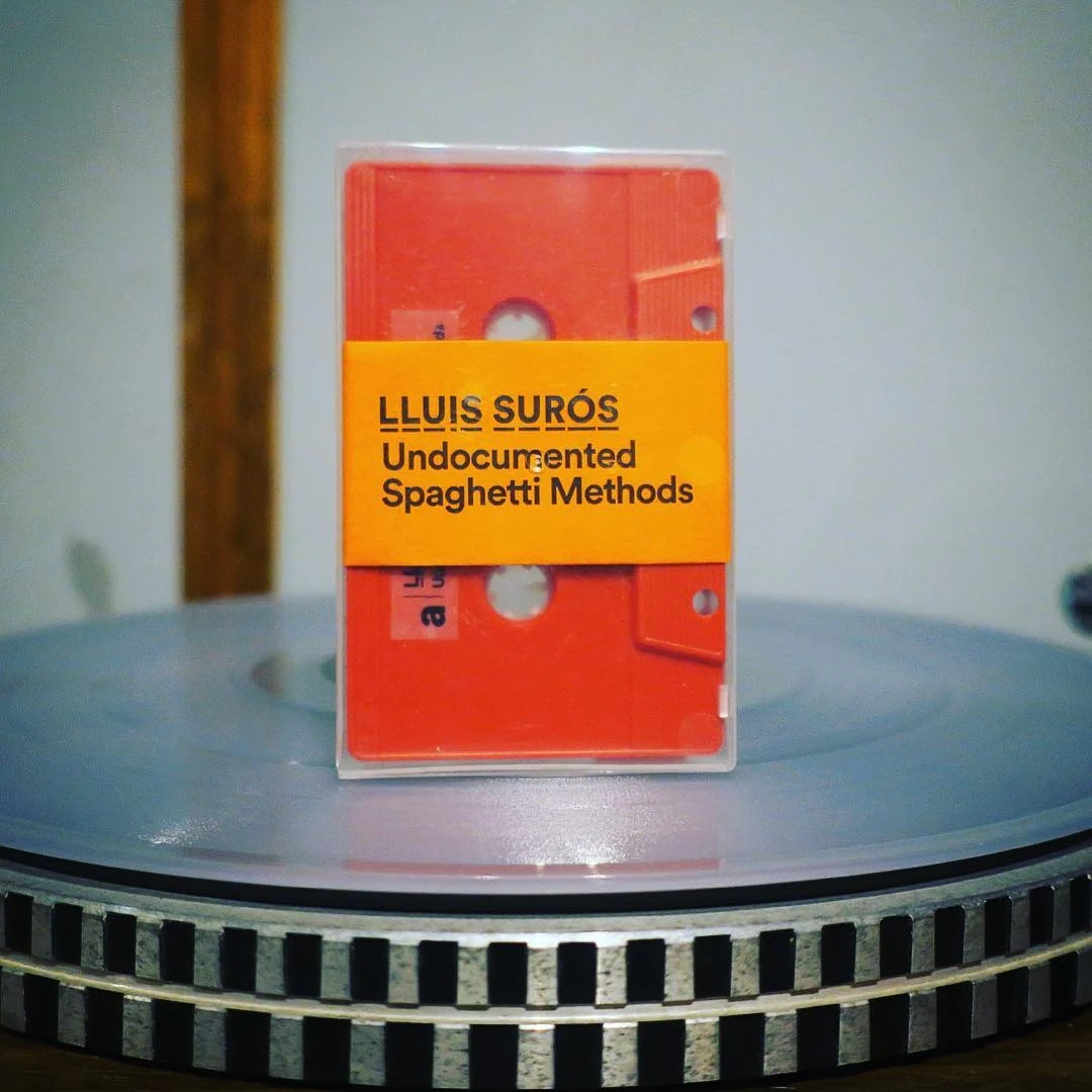 Cassette tape labelled "Lluis Surós — Undocumented Spaghetti Methods" standing on a turntable platter